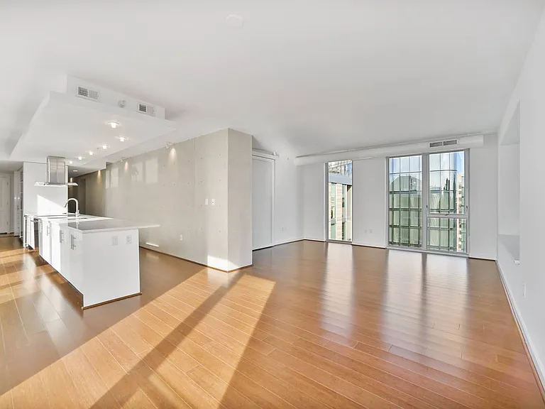 Soak in natural light in this expansive open-concept apartment featuring a sleek kitchen island and panoramic floor-to-ceiling windows.