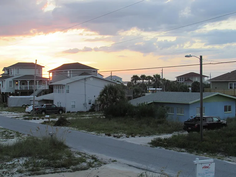 Sunset view of our cozy cottage which is the blue and green building to the right of the picture.