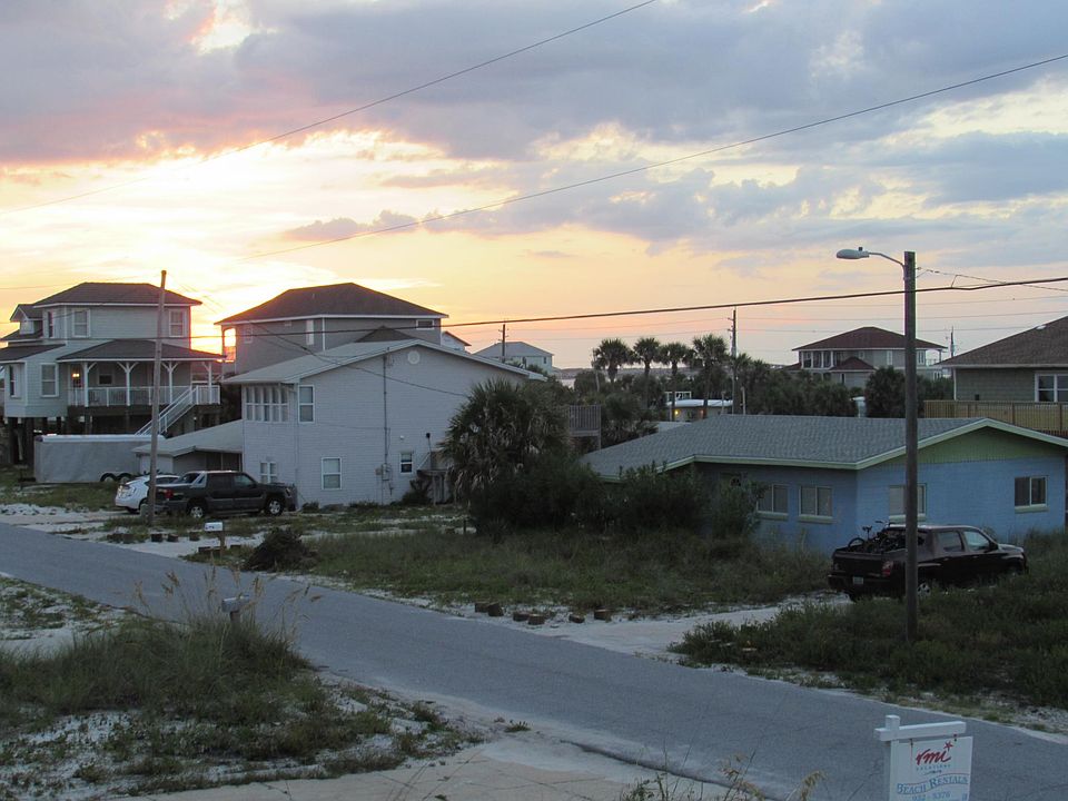 Sunset view of our cozy cottage which is the blue and green building to the right of the picture.