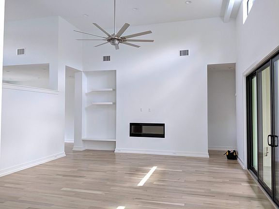 Large open Living room with white oak hardwood floors separated from front entry by a half wall for privacy and to allow natural light throughout home. Electric fireplace that can be used with or without heated air. This space opens to kitchen and to pati