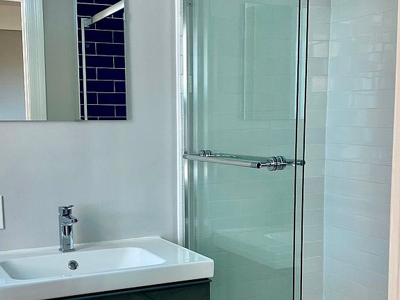 New glass enclosure, tiles, plumbing, and fixtures in bathroom.