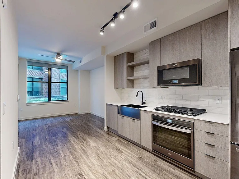 Apartment Kitchen with Stainless Steel Appliances and Living Room with Wood Style Flooring