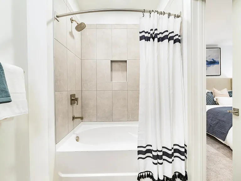 A clean-lined bath with a tiled tub surround and built-in niche, offering a comfortable setting for unwinding at the end of the day.