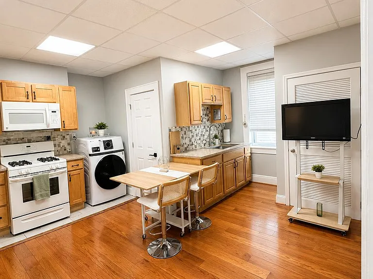Spacious kitchen with wood cabinetry, gas range, microwave, sink, and a small eat-in table plus in-room laundry.