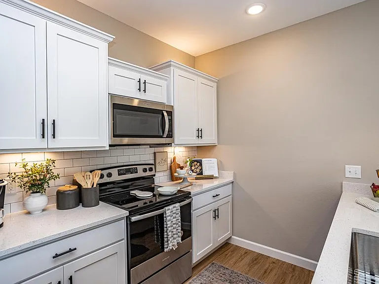 Kitchen featuring stainless steel appliances and quartz countertops, offering both style and functionality. Ample cabinet space, a breakfast bar with pendant lighting and a closet pantry make this kitchen perfect for cooking and entertaining.