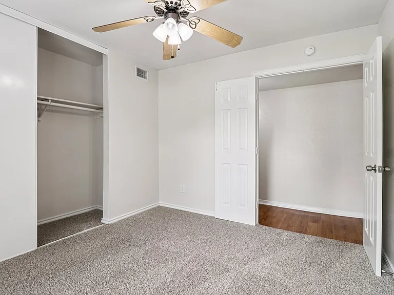 Bright, inviting bedroom with plush carpet, ceiling fan, and open closet space, perfect for comfort and organization. Bright, inviting bedroom with plush carpet, ceiling fan, and open closet space, perfect for comfort and organization.