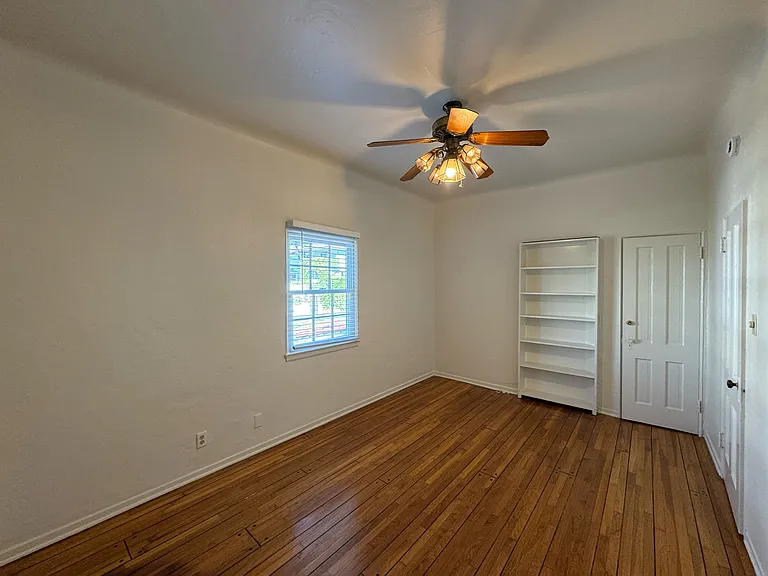 Downstairs bedroom - hardwood floors, ceiling fan, closet, and built-in shelf door to the basement storage.