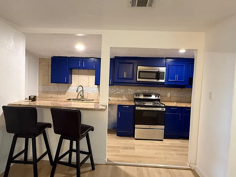 Updated kitchen with blue cabinetry, ample counter space, tiled backsplash, and a breakfast bar for casual seating.