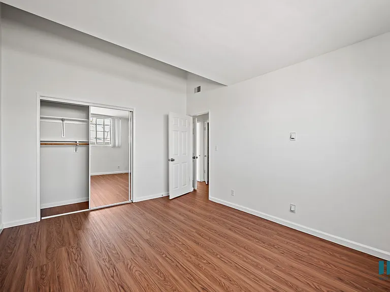 Bedroom with a Mirrored Closet and Hardwood Flooring