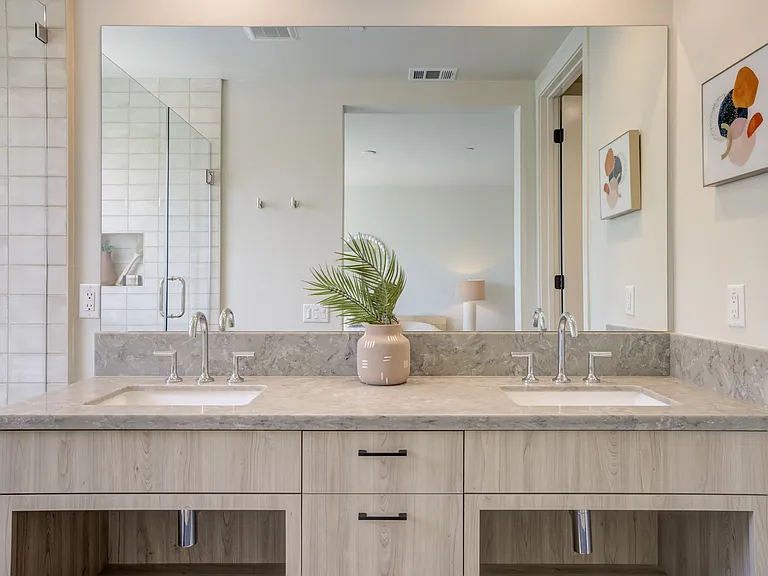 Primary bathroom featuring a private enclosed toilet room, walk-in shower, and dual vanity sinks.