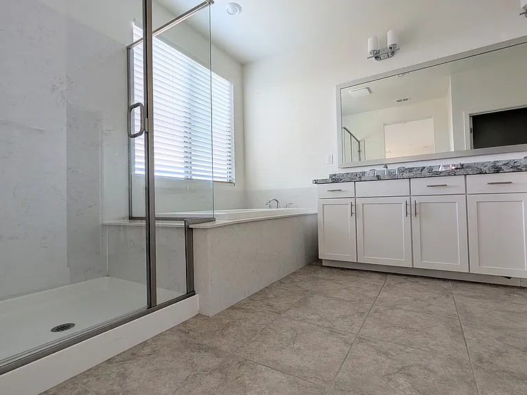 Unwind in your spa-inspired master bathroom featuring a dual-sink vanity, deep soaking tub, and sleek glass shower. This sanctuary is designed for ultimate luxury, serving as your perfect retreat for daily rejuvenation.