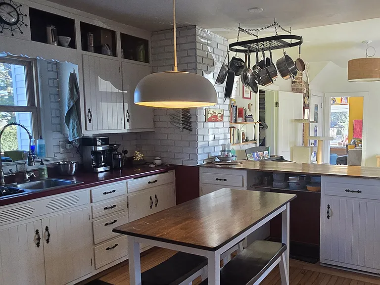 The kitchen has many wood cabinets and the window faces east with a view