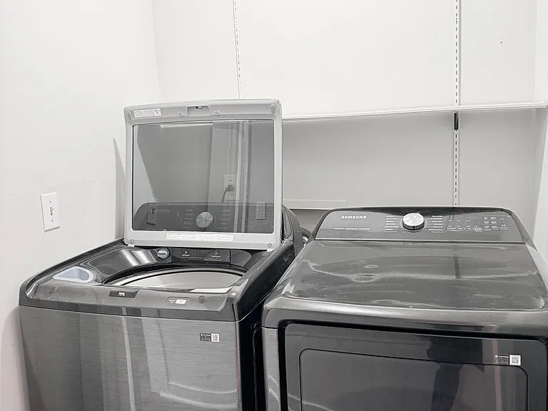 Dedicated laundry area with side-by-side washer and dryer and adjustable wall shelving for supplies and storage.