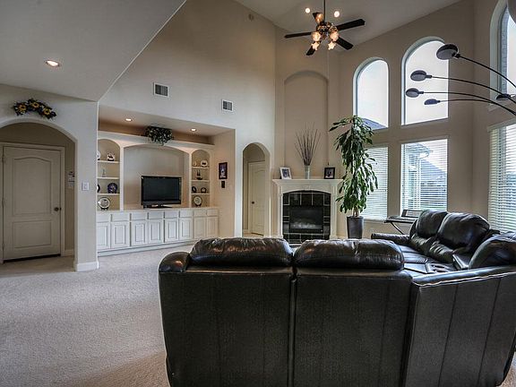 The expansive family room has arched two story picture windows, built in cabinetry and a fireplace topped with an elegant art niche. The bottom windows have two inch blinds. Lovely neutral colors can fit with any decor.