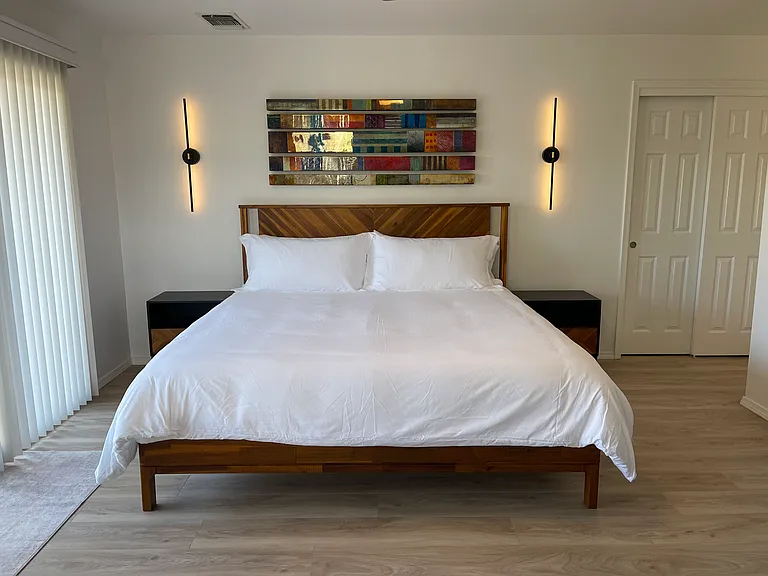 Primary Bedroom with king bed, 2 nightstands, 2 wall lights, closet, and huge patio door with access to the fire pit seating area outdoor deck