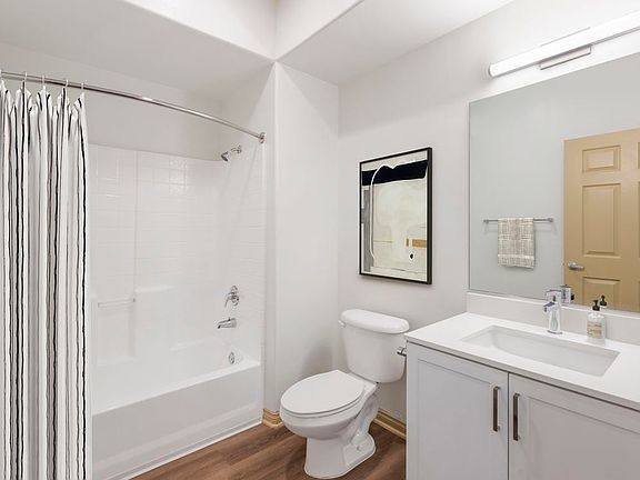 Renovated Package I bath with white speckled quartz countertop, white cabinetry, and hard surface flooring
