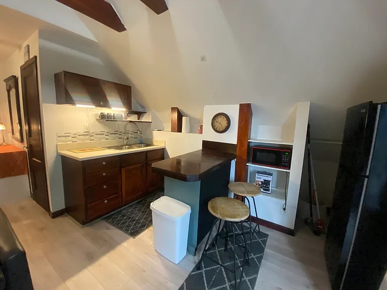 The kitchen has a custom vintage island, stone countertop, sink, microwave, utensils, more.