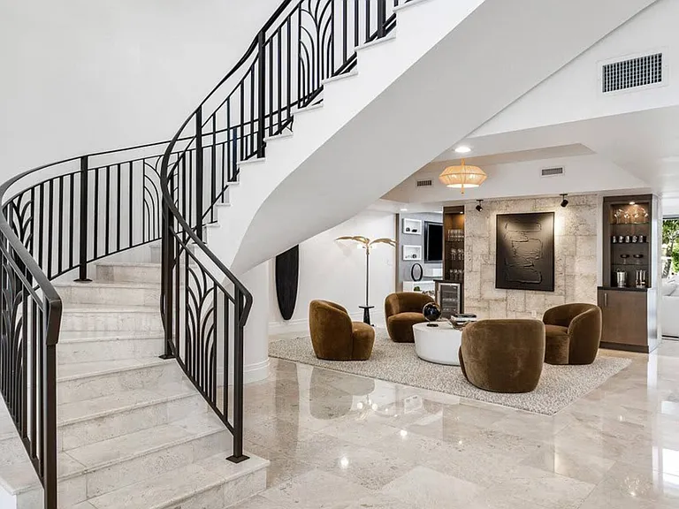Elegant staircase with custom wrought-iron details and polished stone steps for a luxurious entrance.