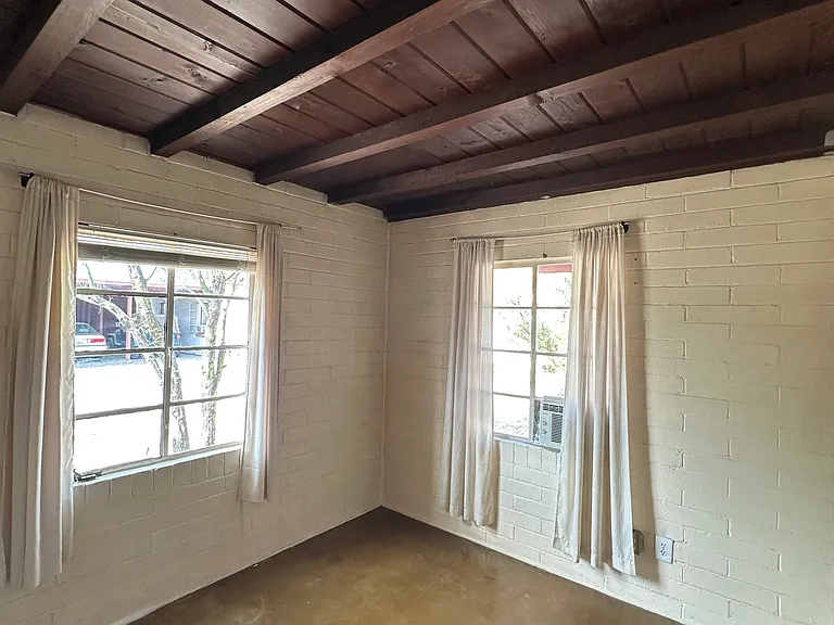 North bedroom with tongue and groove ceiling, colored concrete floors and window AC