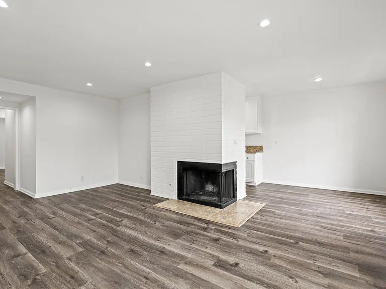 Open-Concept Dining and Living Room Space with an Electric Fireplace, Vinyl Flooring, and Recessed Lighting
