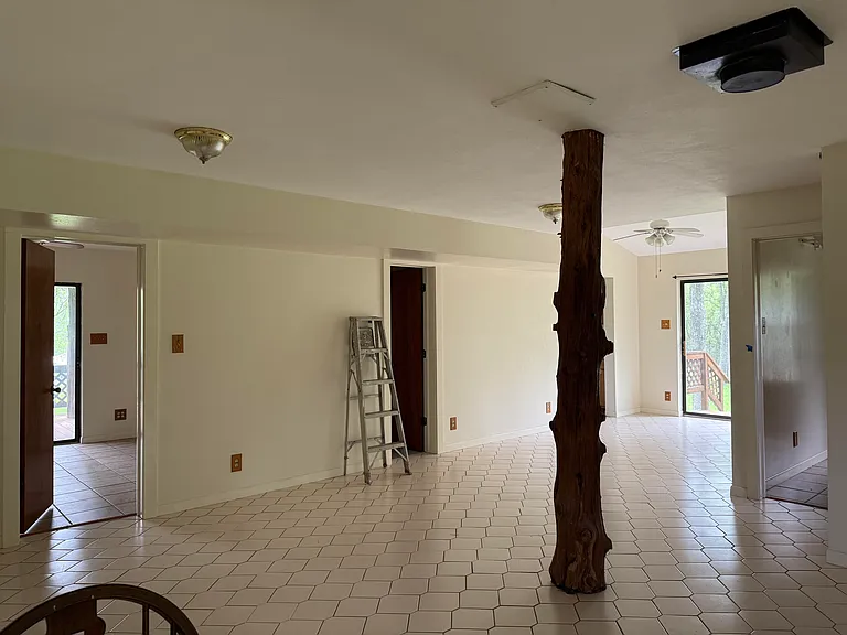 Living room and dining area showing a (from the left) a bedroom entrance, bathroom entrance, kitchen entrance (behind the pole), and to the right, another bedroom.