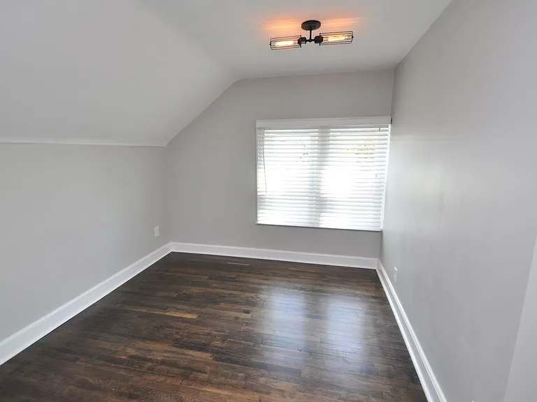 Medium bedroom with maple hardwood floors, exposed brick (see other photo), new paint, and funky Edison bulb fixture with dimmer switch