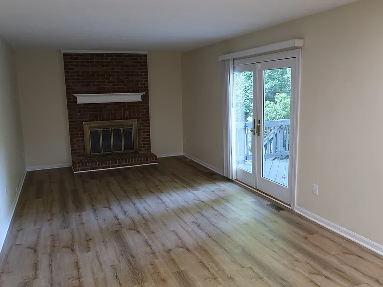 Family room leading to deck, new LVP flooring, wood burning fireplace.