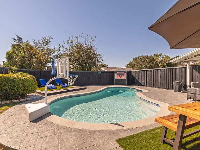Go swimming in the pool with sun loungers, an umbrella, a floaters rack, pool lights, a basketball hoop as well as a beautiful view of the property in this fully-fenced yard.