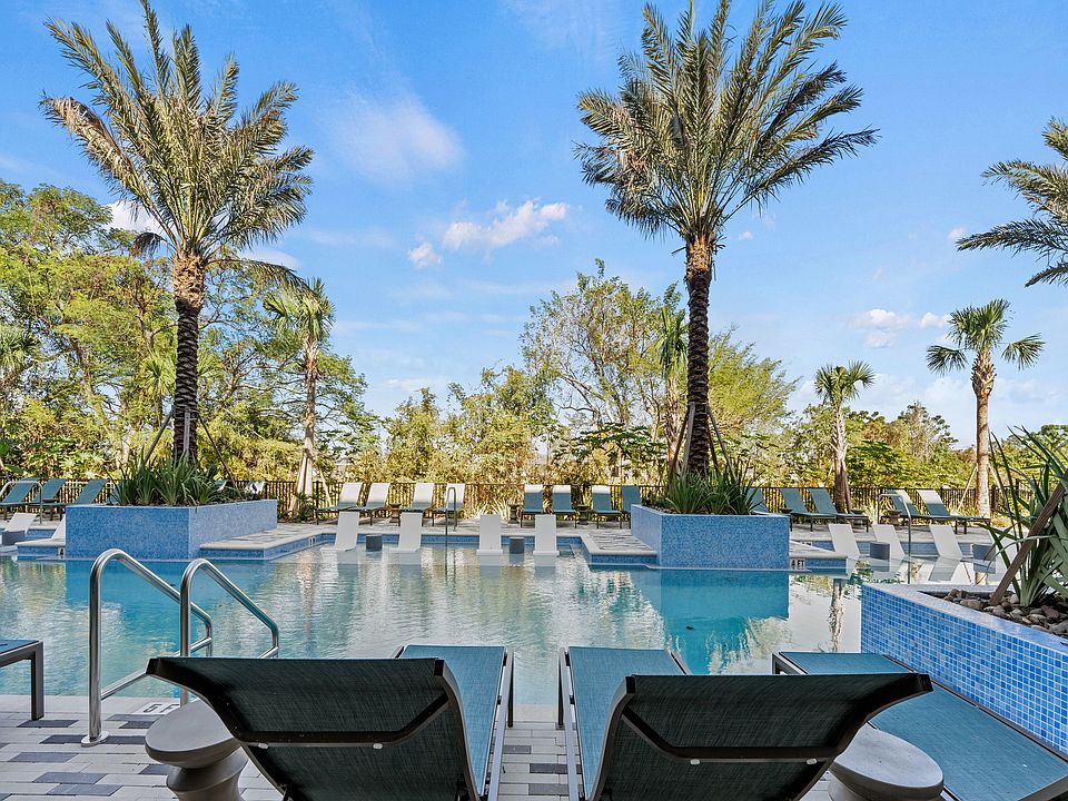 Luxurious pool area with elegant lounge chairs and towering palm trees, set against a stunning blue sky backdrop.