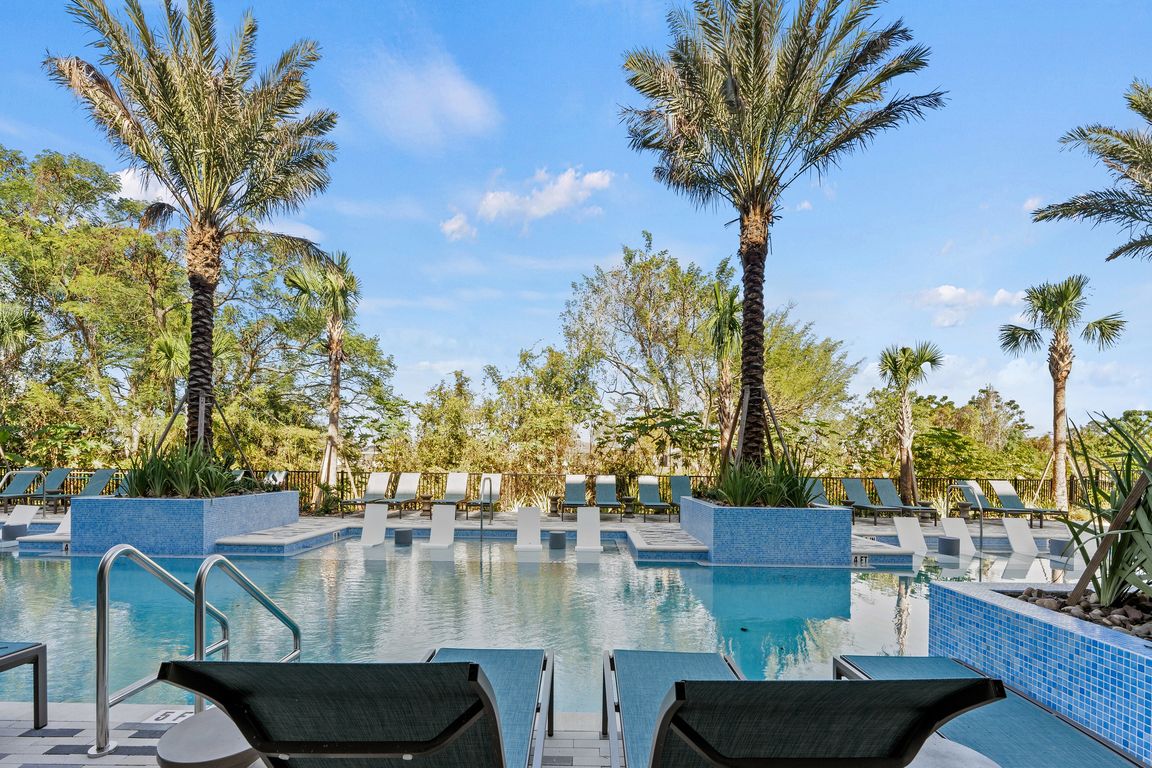 Luxurious pool area with elegant lounge chairs and towering palm trees, set against a stunning blue sky backdrop.