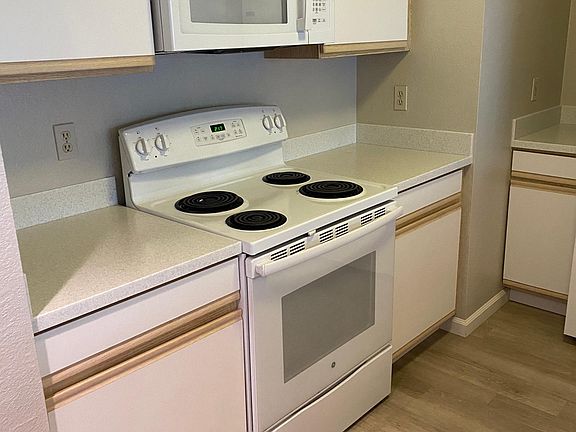 View of half the kitchen with oven, cooktop and microwave