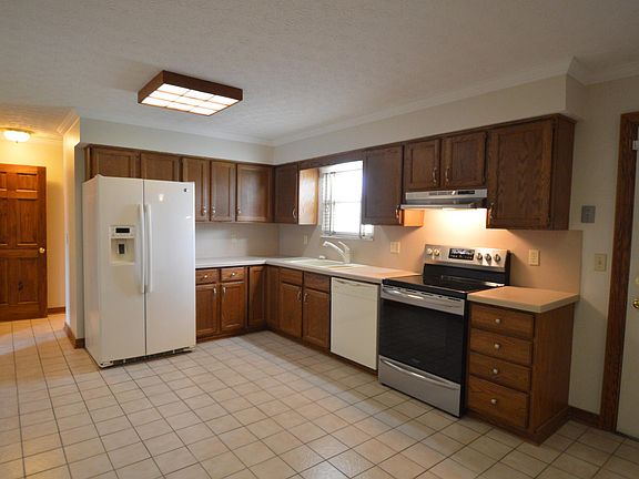 Kitchen features tile floors, neutral paint, and back door to patio and yard.