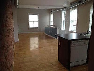 Empty view of living and dinning area in front of kitchen. Stairwell on the right.