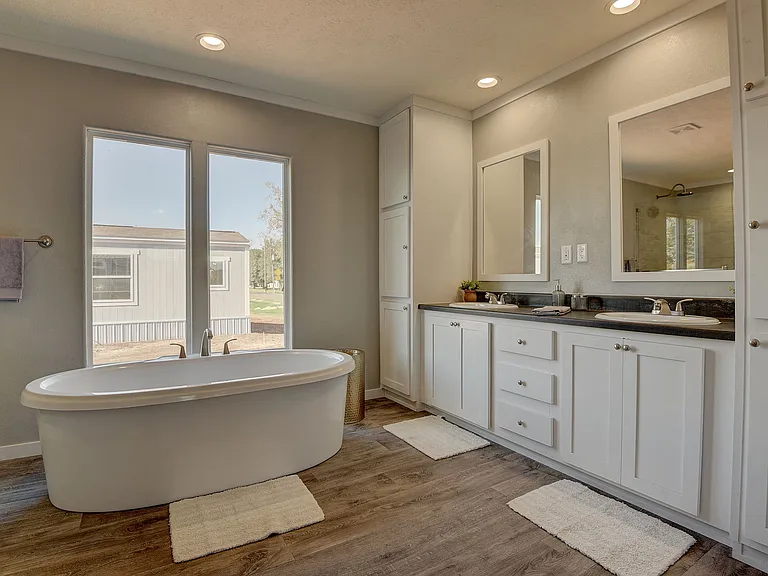 Spa-like primary bathroom featuring a freestanding soaking tub, dual vanities, and abundant natural light_designed for a relaxing, high-end retreat.