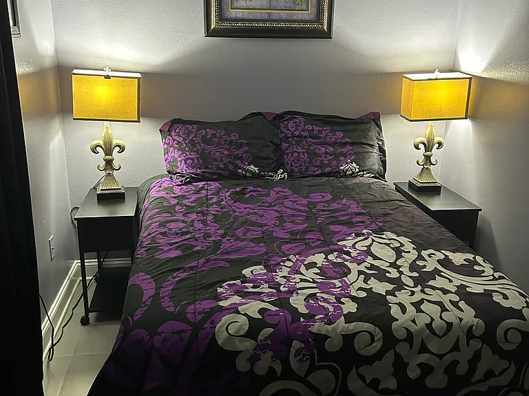 back bedroom with private bathroom features a full sized bed and tv