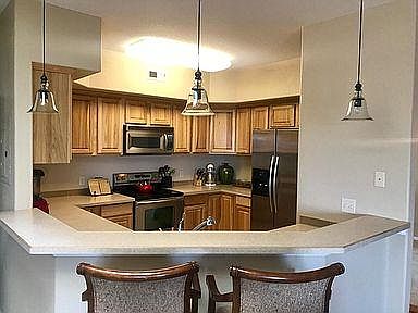 Kitchen with stainless steel appliances. Enough room for four barstools.