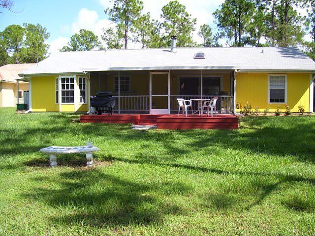 back of house with wood deck and screen lanai