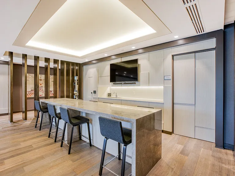 Modern clubroom featuring a kitchen and stylish bar seating
