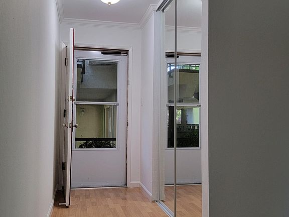 Entryway with laminated floor and large closet with mirrored doors