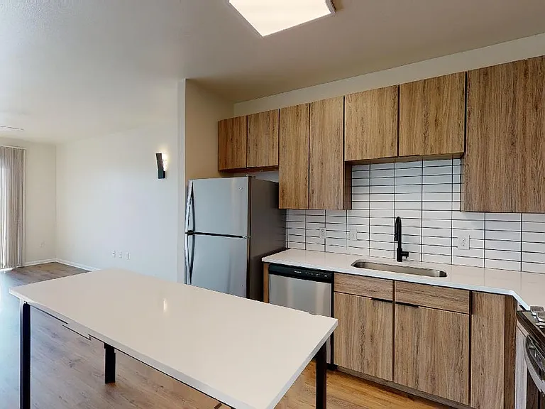 Apartment kitchen with stainless steel appliances, quartz countertops and wood-style flooring.