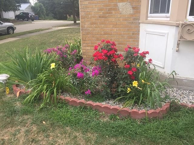 Sibley unit has flowerbeds, trees and roses surrounding it like this one