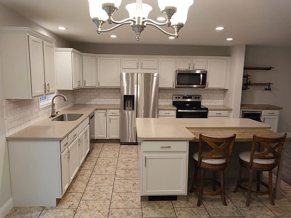 Spacious gourmet kitchen with oversized island, stainless steel appliances, subway tile backsplash, and walk-in pantry