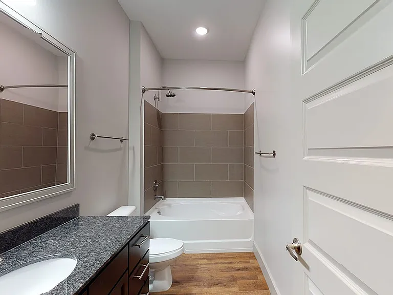 Apartment bathroom with large soaking tub and wood-style flooring.