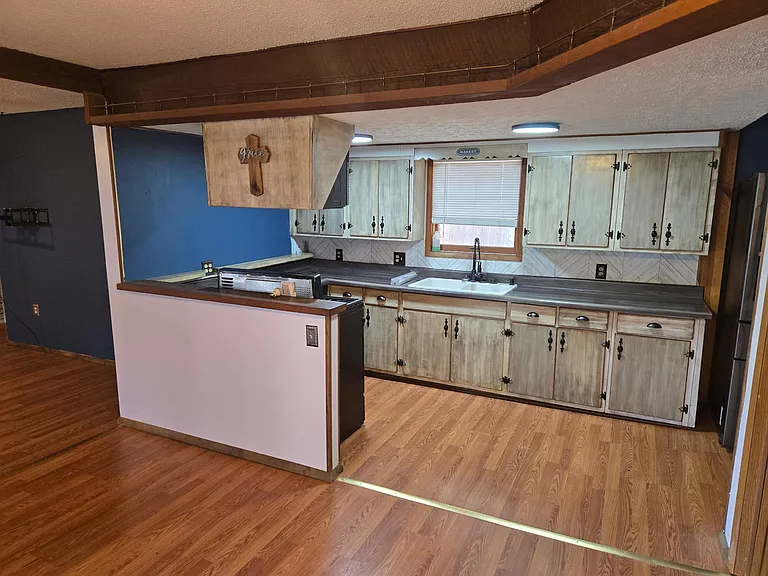 Freshly remodeled kitchen with custom antiqued cabinets, garbage disposal, faux butchers-block laminate countertops, dishwasher, gas stove, overhead microwave, and three-drawer fridge!