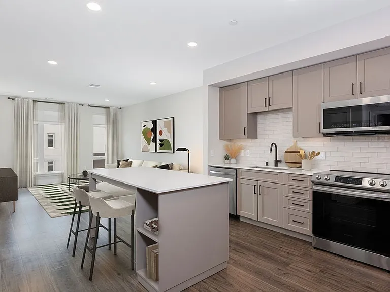 Finish Package II Kitchen with beige cabinetry, white tile backsplash, white quartz countertops, stainless steel appliances, and hard surface flooring