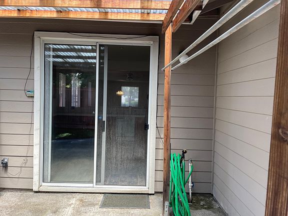 Backyard with hose area and hanging area for cloths with sliding glass door access to kitchen.