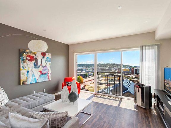 A spacious living room with large windows and a sliding glass door leadnig out to the Juliet balcony