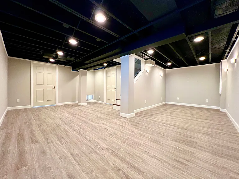 400sf finished basement with vinyl plank. Dimmable lighting. Sconces in entertainment area. Left door to unfinished workshop. Right door to laundry and unfinished storage.