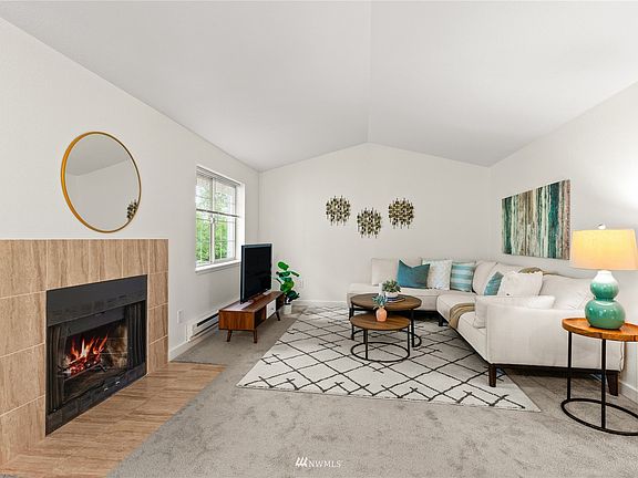 A beautiful living room with vaulted ceilings and wood burning fireplace awaits a new owner who loves an open space to entertain and enjoy the tree top views.