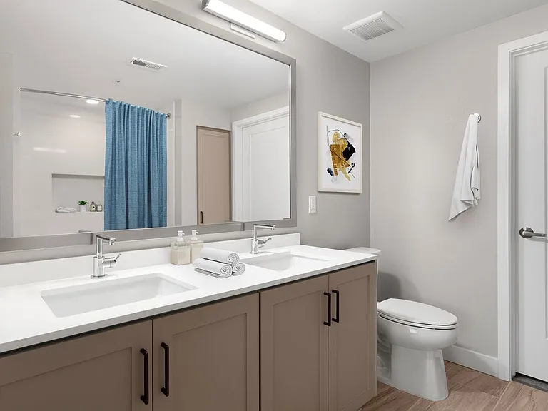 Townhome bath with white quartz countertops, brown cabinetry, and hard surface flooring (select homes)
